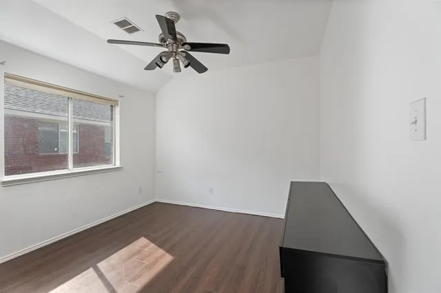 a view of a hallway with wooden floor and a chandelier fan