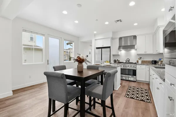a kitchen with stainless steel appliances kitchen island granite countertop a sink a stove a table and chairs