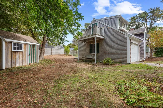 a backyard of a house with plants and large tree