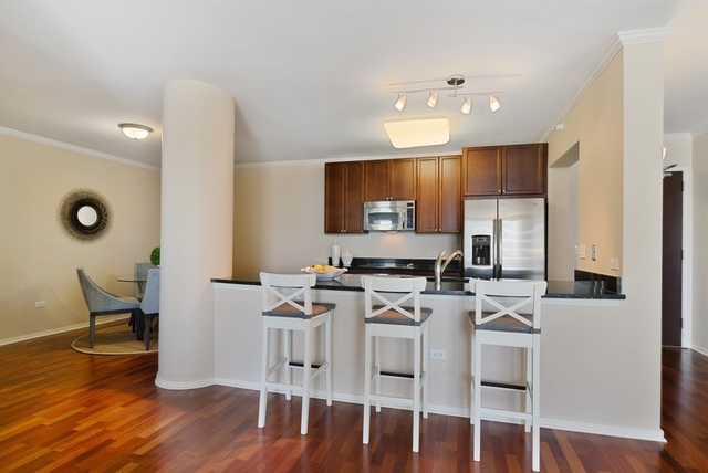807 Davis Street, Unit 1504 Evanston, IL 60201 - Photo 4 of 14 a kitchen with stainless steel appliances granite countertop a stove top oven a sink a dining table and chairs with wooden floor