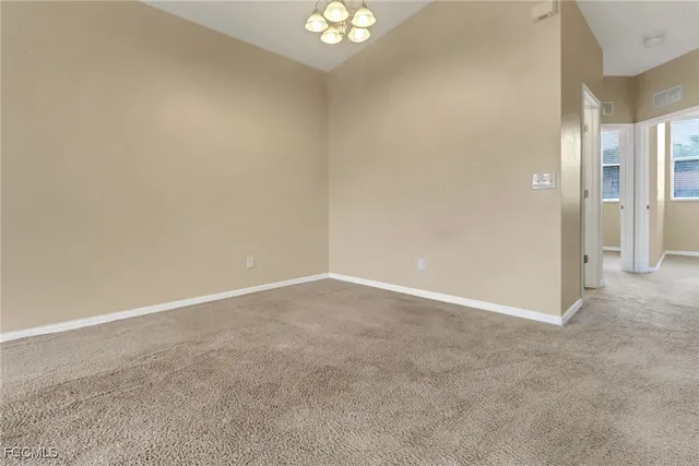 a view of an empty room and a chandelier fan