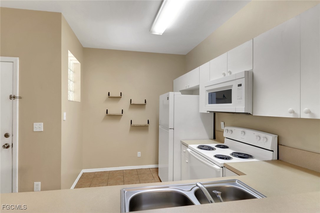 4214 Bellasol Circle, Unit 824 Fort Myers, FL 33916 - Photo 4 of 27 a kitchen with stainless steel appliances kitchen island a stove a refrigerator and white cabinets
