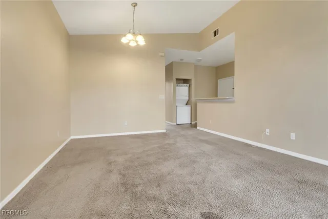 a view of an empty room with a chandelier fan