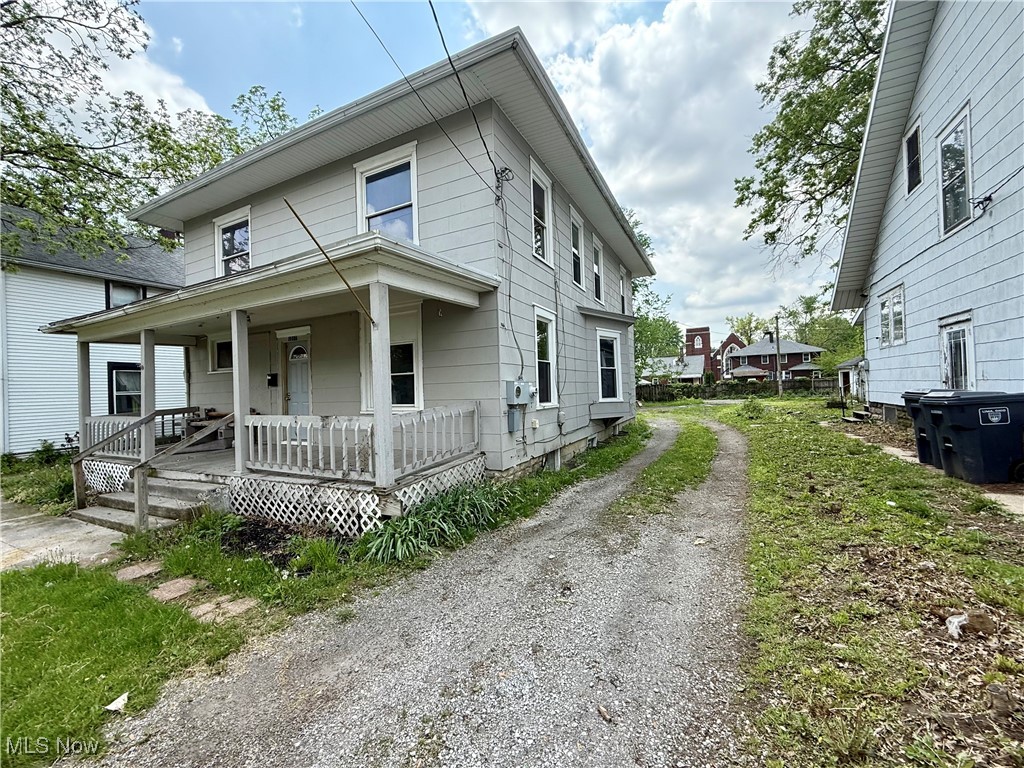 American foursquare style home featuring covered porch and dirt driveway