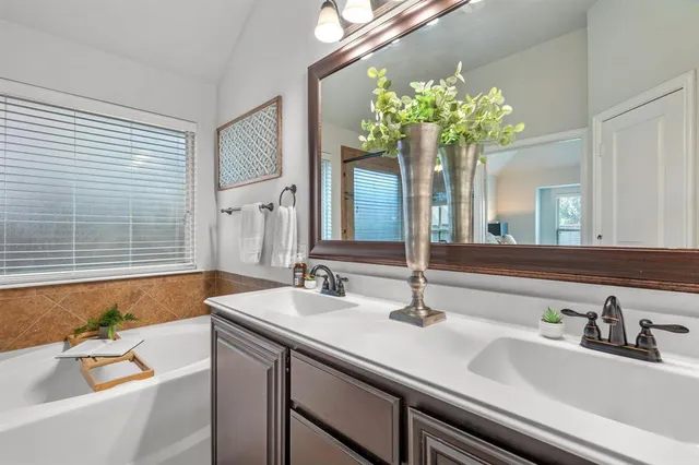 a bathroom with a bathtub a sink a large mirror and a bathtub