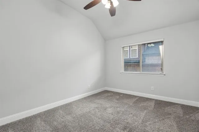 an empty room with chandelier fan and windows