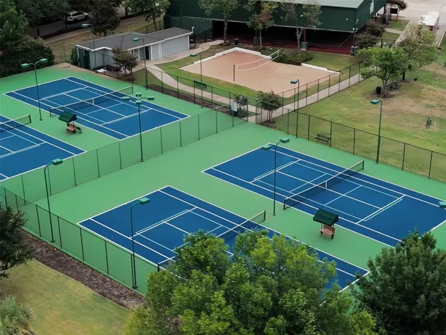 a view of a tennis ground with large trees