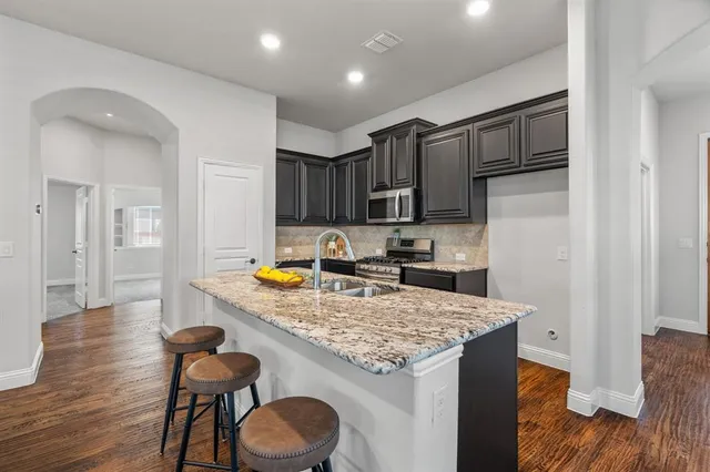 a kitchen with granite countertop kitchen island wooden cabinets a refrigerator stove a sink and dishwasher