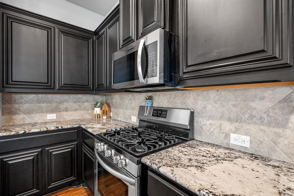 1609 Emerald Tree Place Aubrey, TX 76227 - Photo 7 of 39 a kitchen with stainless steel appliances granite countertop a stove and a microwave