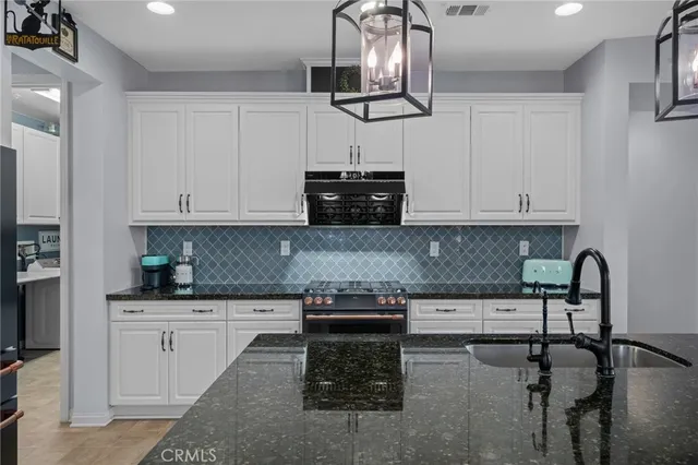 a kitchen with granite countertop white cabinets and black appliances