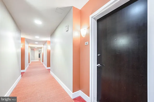 a view of a hallway with wooden floor and a bathroom