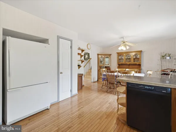 a kitchen with stainless steel appliances granite countertop a refrigerator a sink dishwasher a stove and a dining table with wooden floor