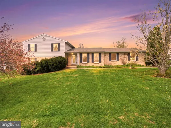 a front view of a house with a garden and trees