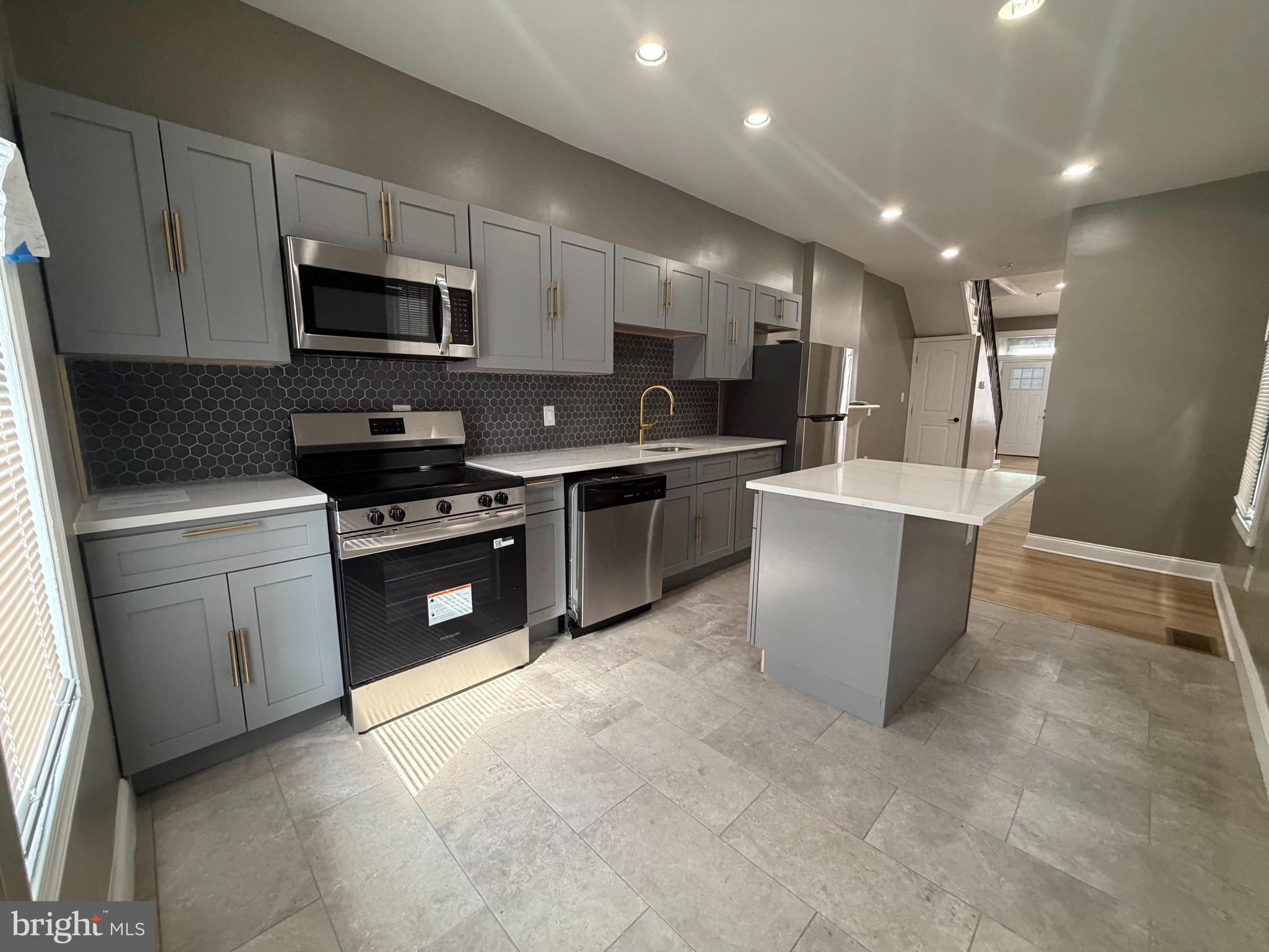2260 North 18th Street Philadelphia, PA 19132 - Photo 5 of 13 a kitchen with stainless steel appliances a microwave a sink a stove a microwave a sink a refrigerator and cabinets