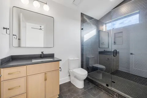 a bathroom with a granite countertop sink a mirror and a toilet