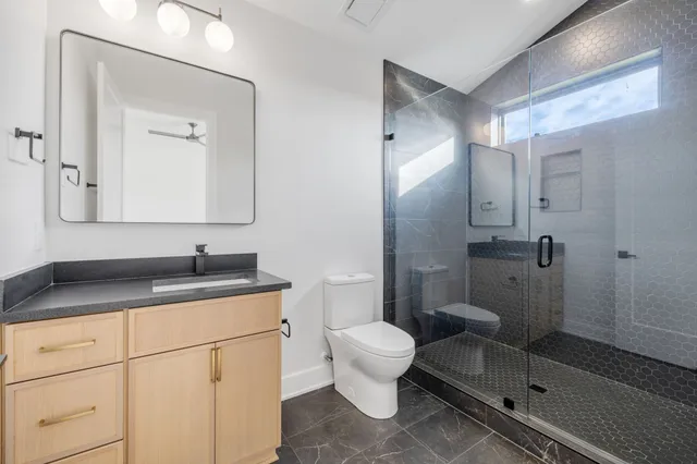 a bathroom with a granite countertop sink a mirror and a toilet