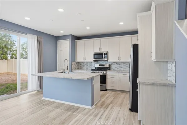 a kitchen with stainless steel appliances granite countertop a refrigerator a sink dishwasher a stove and white countertops with wooden floor