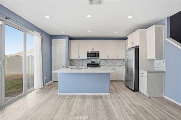 a view of kitchen with kitchen island stainless steel appliances a sink and refrigerator