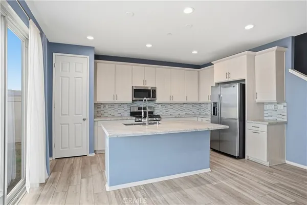 a big room with wooden floor a ceiling fan and a bathroom