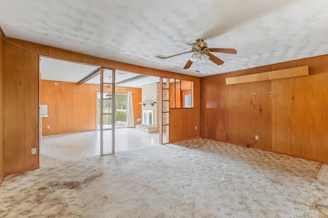 a view of a livingroom with a fireplace large windows and wooden floor