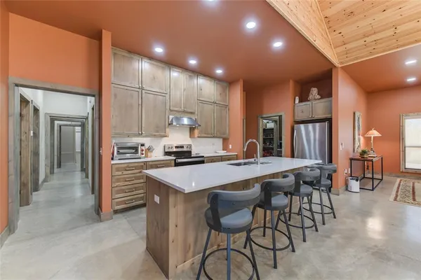 a kitchen with stainless steel appliances a table chairs refrigerator and cabinets