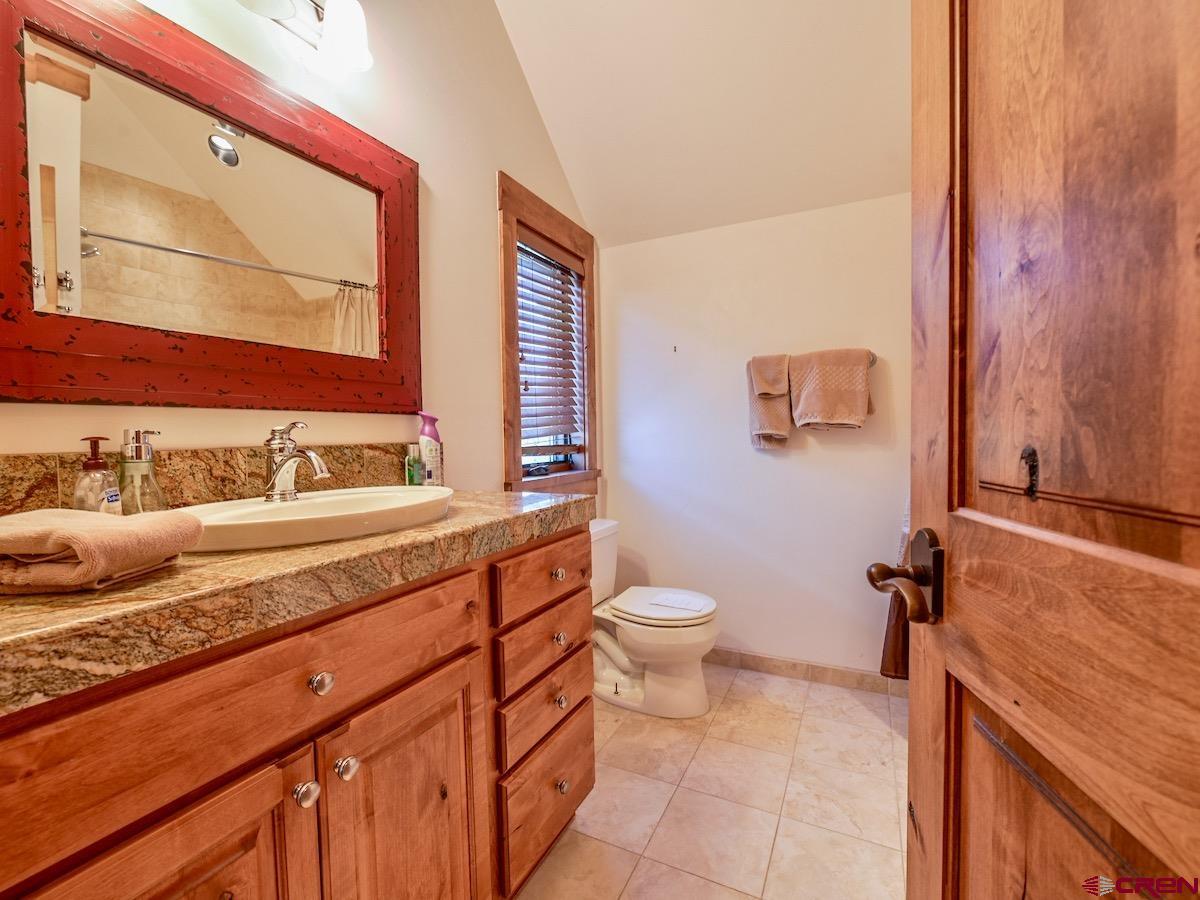 930 Gothic Road Crested Butte, CO 81225 - Photo 16 of 35 a bathroom with a granite countertop sink mirror vanity and toilet