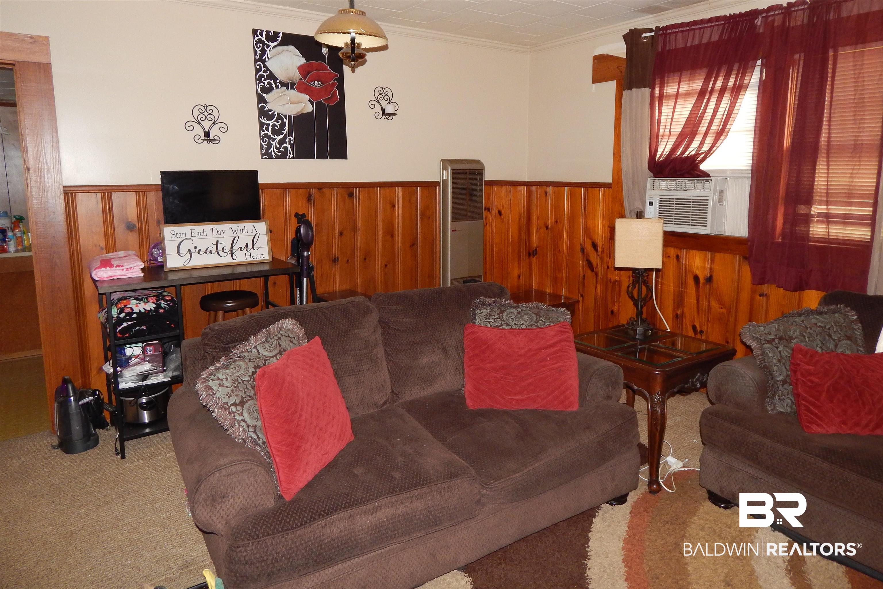 309 Bellview Avenue Evergreen, AL 36401 - Photo 4 of 27 Carpeted living room with wooden walls, wainscoting, ornamental molding, and cooling unit