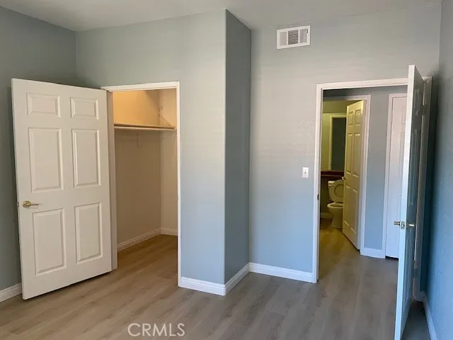 an empty room with wooden floor bathroom and closet