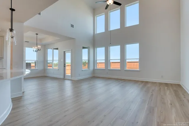 a view of an empty room with kitchen and window