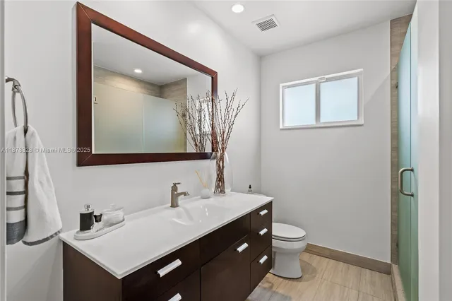 a bathroom with a toilet a sink a mirror and vanity