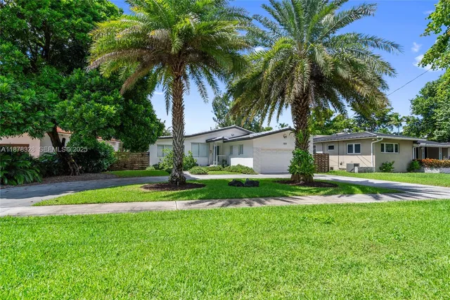 a view of a house with a yard and palm trees