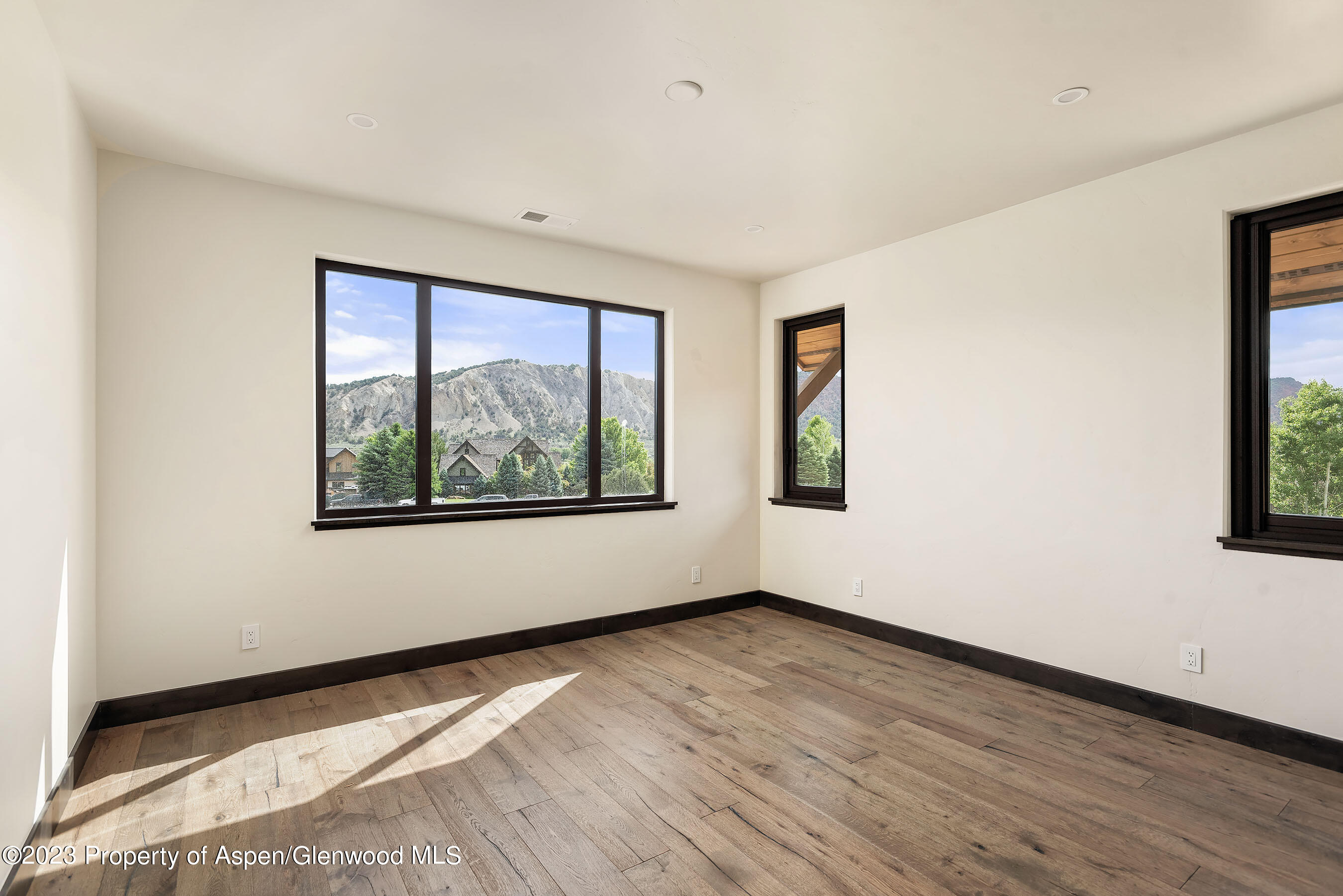 151 Sundance Trail Carbondale, CO 81623 - Photo 13 of 22 an empty room with wooden floor and windows