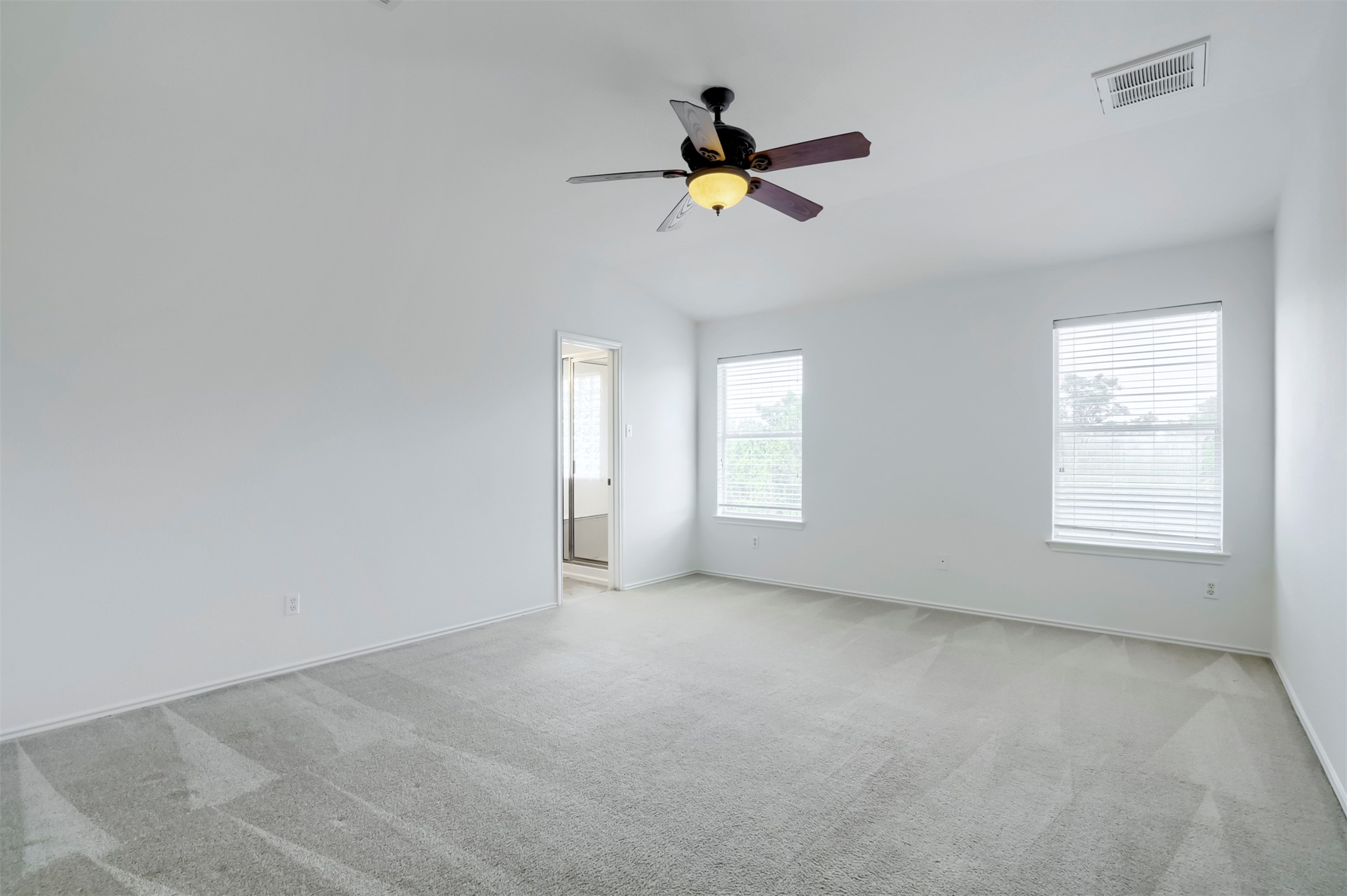 4125 Pebble Ridge Cove Round Rock, TX 78681 - Photo 17 of 30 A spacious primary bedroom features soft carpet flooring, high ceilings, and two windows allowing for ample natural light.