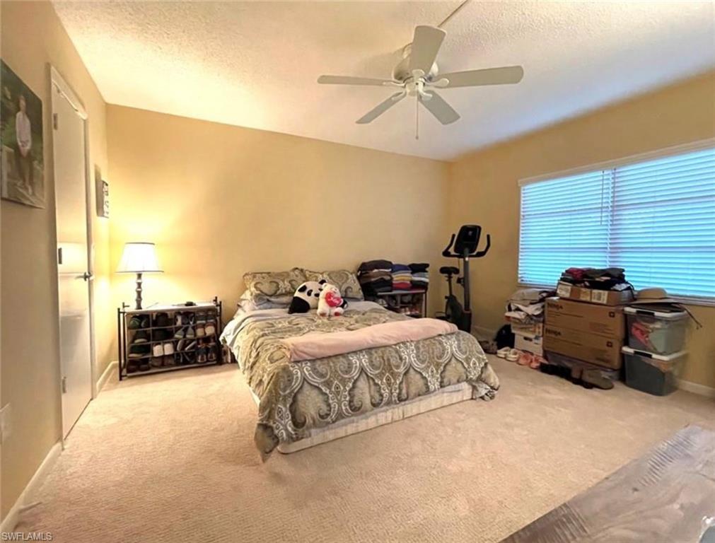 201 Quail Forest Boulevard, Unit 208 Naples, FL 34105 - Photo 4 of 8 a bedroom with a bed and a chandelier