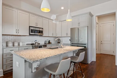 a kitchen with granite countertop a sink and a stove top oven with wooden floor