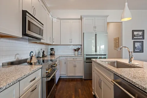 a kitchen with granite countertop a sink a stove and cabinets