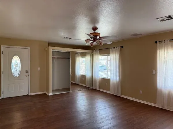 a view of an empty room with window and wooden floor