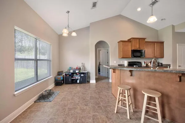 a kitchen with stainless steel appliances granite countertop a stove top oven a sink a dining table and chairs with wooden floor