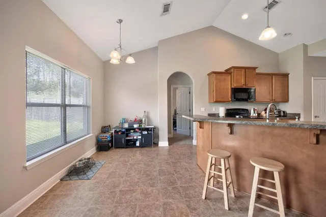 a kitchen with stainless steel appliances granite countertop a stove top oven a sink a dining table and chairs with wooden floor