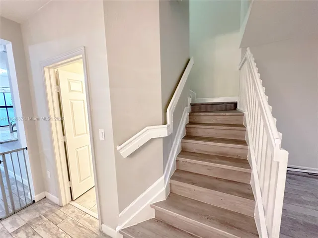a view of staircase with wooden floor and white walls