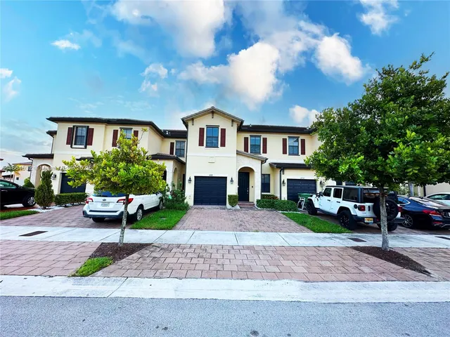 a front view of a house with a garden and trees