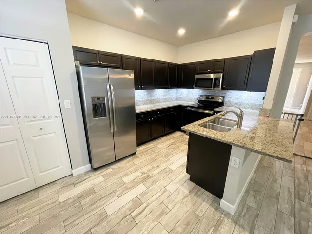 a kitchen with granite countertop a refrigerator and a sink