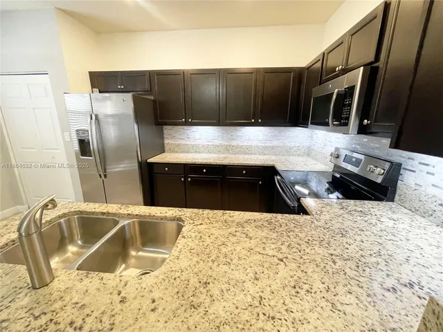 a kitchen with granite countertop a sink and a stove top oven