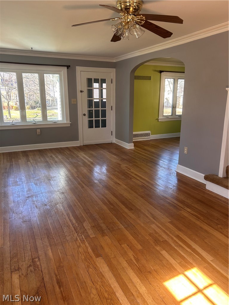 1001 Englewood Road Cleveland Heights, OH 44121 - Photo 10 of 28 Empty room with a ceiling fan, dark wood-style floors, arched walkways, and ornamental molding