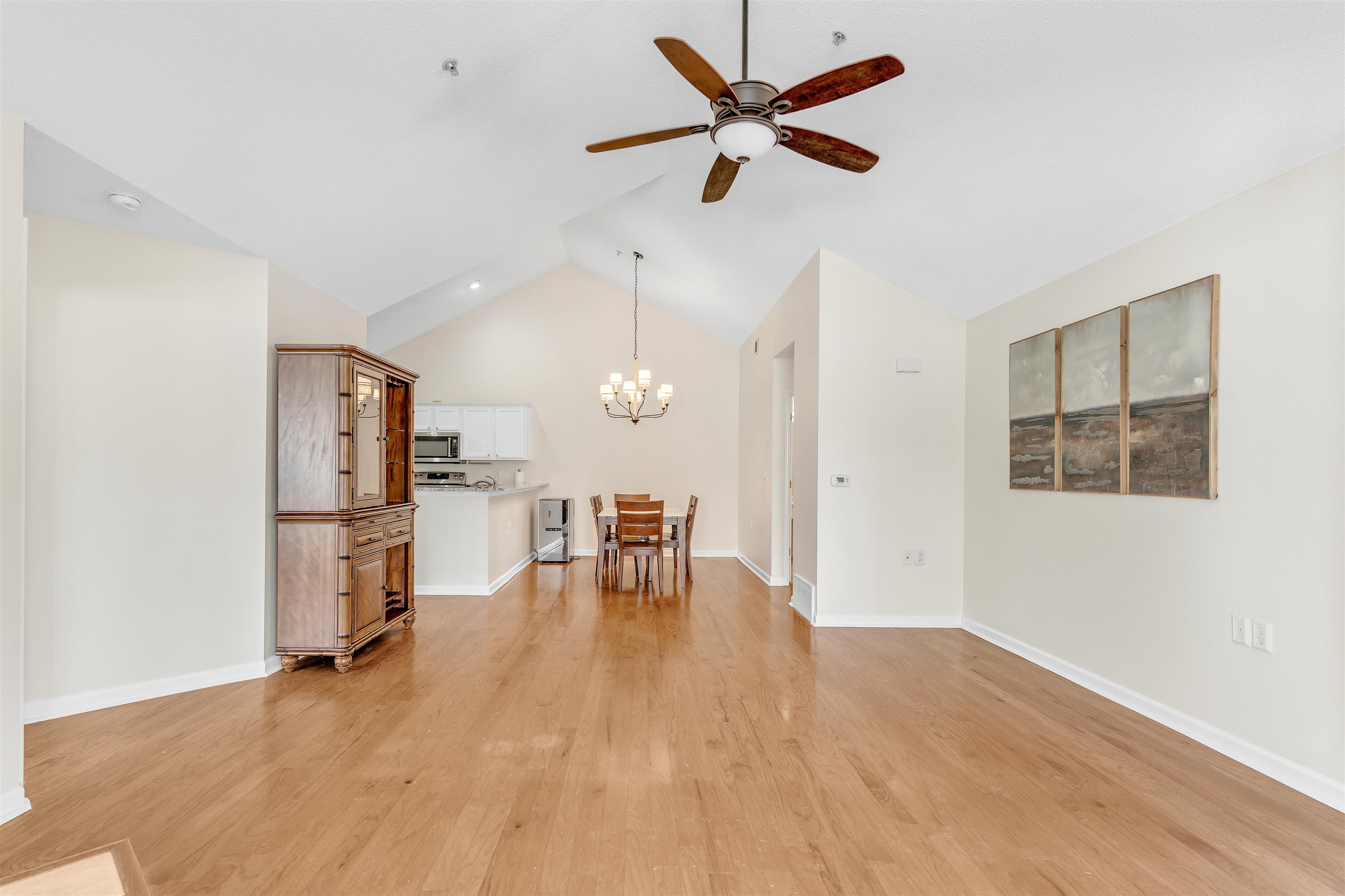 1213 Oak Timber Circle, Unit 25 Collierville, TN 38017 - Photo 7 of 25 Unfurnished living room with lofted ceiling, light wood finished floors, ceiling fan with notable chandelier, and baseboards