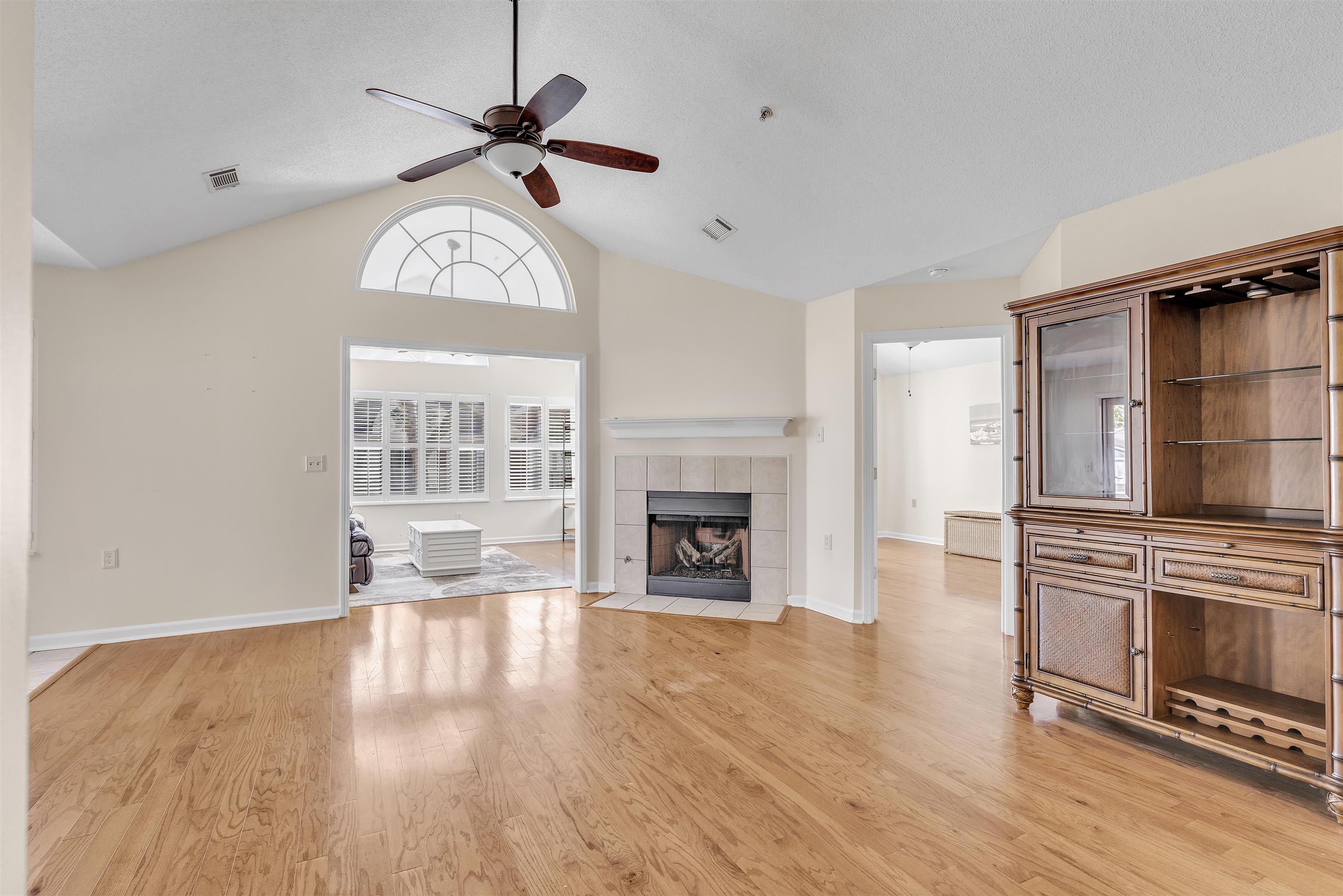 1213 Oak Timber Circle, Unit 25 Collierville, TN 38017 - Photo 9 of 25 Unfurnished living room with a tiled fireplace, light wood-type flooring, lofted ceiling, and visible vents
