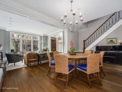 a dining room with wooden floor a chandelier a glass table and chairs