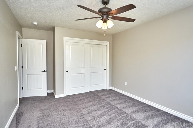 22227 Skyline Drive Apple Valley, CA 92308 - Photo 10 of 34 an empty room with a chandelier fan and closet area