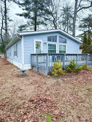 a view of a house with a small yard and large trees