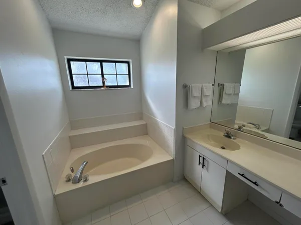 a bathroom with a tub sink and mirror